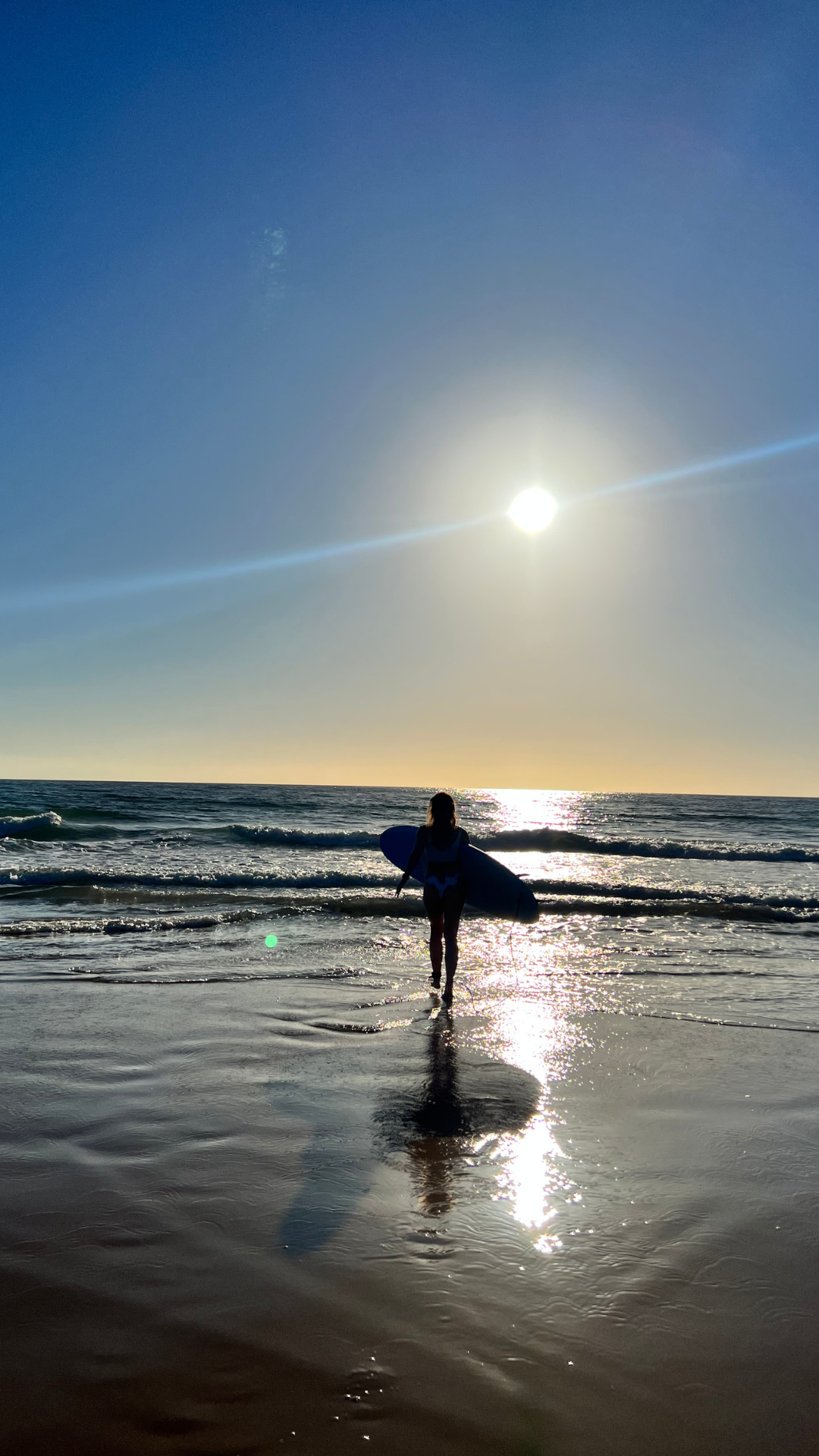 Surferin mit Board im Sonnenuntergang am Meer